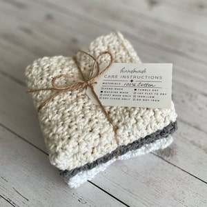A stack of 3 neutral colored handmade dishcloths tied together with twine and topped with a care instruction label