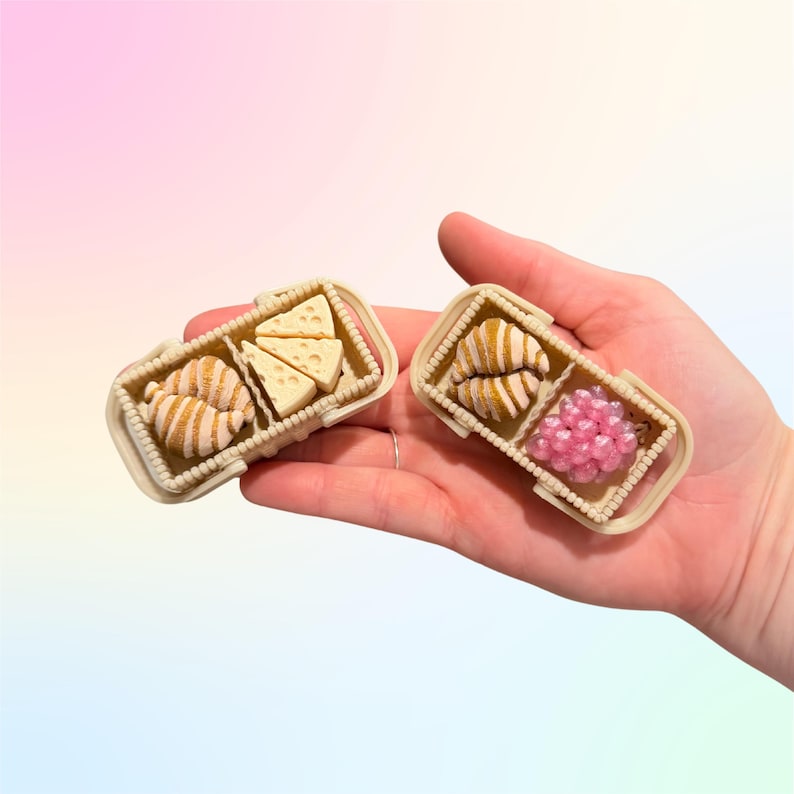 Puede incluir: Mini cestas de picnic en miniatura con alimentos. Una cesta contiene un cruas&aacute;n y cu&ntilde;as de queso. La otra cesta tiene un cruas&aacute;n y esferas rosas. Las cestas son beige con un dise&ntilde;o tejido.
