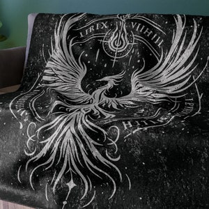 Könnte beinhalten: Schwarze und weiße Tagesdecke mit einem Phönix-Design und den Worten "Urix VIIIII" in einem Kreis um den Phönix.