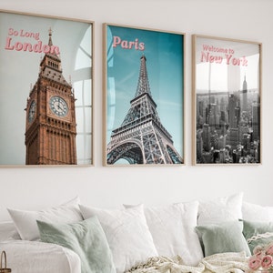 May include: Three framed prints with cityscapes. The first print features Big Ben in London with the text "So Long London". The second print features the Eiffel Tower in Paris with the text "Paris". The third print features the New York City skyline with the text "Welcome to New York".