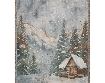 May include: A woven tapestry depicting a charming cabin nestled in a snowy mountain landscape. The cabin has a wooden exterior and a snow-covered roof. The scene is painted in shades of brown, white, and blue, with a light dusting of snow falling from the sky.