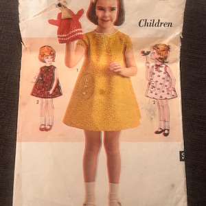 May include: Vintage sewing pattern featuring a child's dress design. The pattern cover shows a girl in a yellow dress, along with illustrations of other dress styles. The text reads "Sew-Easy ADVANCE" and "Children, Size 4".
