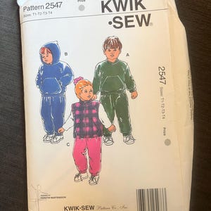 May include: A Kwik Sew pattern packet, model 2547, showing illustrations of children's tracksuits. The packet includes a blue hooded tracksuit, a green tracksuit, and a pink and plaid vest outfit. The pattern is designed by Kerstin Martensson.