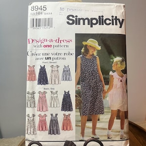 Puede incluir: Patrón de costura Simplicity para diseñar un vestido con un patrón. El paquete presenta ilustraciones de varios diseños de vestidos, junto con una foto de dos personas que llevan vestidos. El texto incluye "Design-a-dress" y "Créez une votre robe".