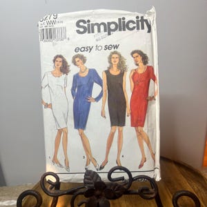 Puede incluir: Un paquete de patrones de costura Simplicity con ilustraciones de cuatro diseños de vestidos diferentes. El paquete es blanco con el logotipo de Simplicity y el texto "easy to sew". Los vestidos son blancos, azules, negros y rojos.