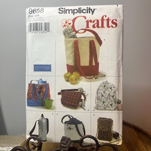 May include: Simplicity Crafts pattern featuring various bag designs. The pattern includes a tote bag with red handles, a patterned handbag, a fanny pack, a drawstring bag, a water bottle holder, a striped bag, and a leopard print phone case.