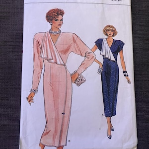 Op de afbeelding: Een vintage naaipatroon getiteld "Very Easy Very Vogue." Het patroon toont illustraties van twee jurken: een lange, lichtroze jurk met een gedrapeerde halslijn en een blauwe polkadotjurk. De patroongrootte is (6-8-10).