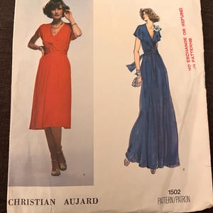 Pode incluir: Padrão de costura Vogue French Boutique com dois modelos de vestidos. Um é um vestido envelope vermelho até o joelho, o outro um vestido envelope longo azul marinho. O padrão é rotulado como "1502 Pattern/Patron" e inclui o nome do designer, Christian Aujard.