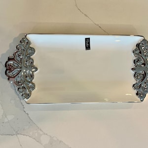 Puede incluir: Una taza de cerámica blanca con un asa negra y el texto "But First, Coffee" en negro y negrita. La taza está sobre una superficie blanca. La taza mide aproximadamente 10 cm de alto.