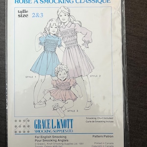May include: A package for a classic yoke dress pattern. The cover features illustrations of three children's dresses in blue, pink, and lavender. Text includes "CLASSIC YOKE DRESS" and "GRACE L. KNOTT SMOCKING SUPPLIES LTD."