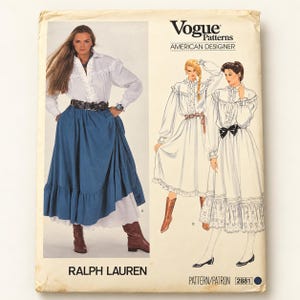 Op de afbeelding: Vogue Patterns American Designer naaipatroon 2881 van Ralph Lauren. De envelop bevat een foto van een wit overhemd met lange mouwen en ruches en een blauwe rok, naast twee illustraties van dezelfde outfit in verschillende stijlen.