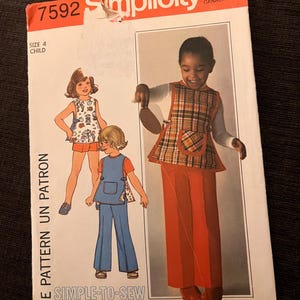 May include: Simplicity pattern 7592 for children's clothing. The image shows a child in a plaid vest and orange trousers, and another in blue overalls. The text "ONE PATTERN UN PATRON" is visible. The price is $1.15.