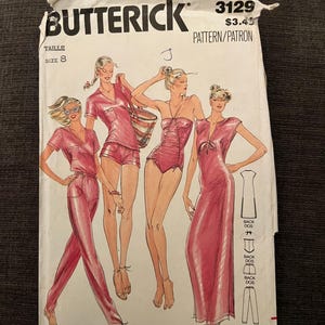 Può includere: Una busta per cartamodello Butterick 3129 taglia 8, con illustrazioni di quattro outfit in tonalità rosa. I modelli includono una tuta, un completo corto, un costume da bagno e un abito lungo di John Kloss, con diagrammi delle viste posteriori.