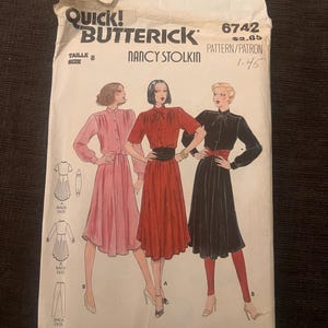 May include: A vintage Butterick sewing pattern envelope featuring illustrations of three dresses. The envelope is labeled "Quick! Butterick" and includes the pattern number 6742. The size is 8. The design is by Nancy Stolkin.