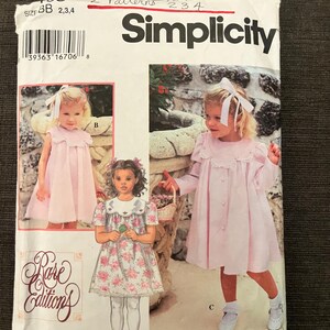 May include: A Simplicity sewing pattern envelope for Rare Editions clothing, featuring illustrations of three different dress styles labeled A, B, and C. The envelope displays size BB 2, 3, 4 and includes a barcode, with images of children wearing the dresses.