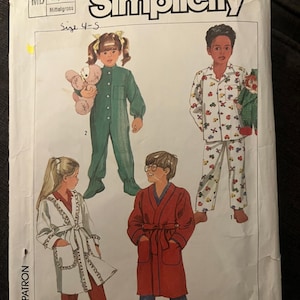 Może przedstawiać: Koperta z wykrojem krawieckim Simplicity na dziecięcą odzież nocną, rozmiar 4-5, klatka piersiowa 22-23 cale. Okładka przedstawia ilustracje czworga dzieci w zielonym śpioszku, wzorzystej piżamie, białym szlafroku z wykończeniem oraz czerwonym szlafroku.