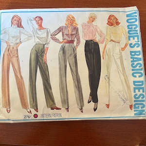 May include: Vogue's Basic Design sewing pattern featuring illustrations of women's fashion. The pattern includes images of blouses and high-waisted pants. The pattern number is 2761. The cover is blue and white.
