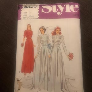 May include: A vintage Style pattern envelope with illustrations of three dresses: a red bridesmaid dress and two white wedding gowns. The envelope has the word "Style" in purple and the text "PATTERN/PATRON". Bust size is 83cm.