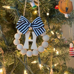 Elegante corona navideña con monograma de letras de madera y lazo de cuentas en tonos neutros - Adorno navideño de bola redonda de madera personalizado para las fiestas