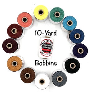May include: A collection of 10-yard bobbins of linen thread in various colors, including yellow, green, blue, red, brown, tan, white, and gray. The bobbins are arranged in a circle with the label "10-Yard Bobbins" in the center.