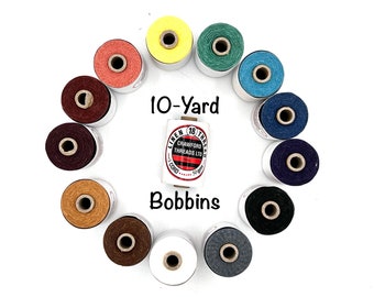 May include: A collection of 10-yard bobbins of linen thread in various colors, including yellow, green, blue, red, brown, tan, white, and gray. The bobbins are arranged in a circle with the label "10-Yard Bobbins" in the center.