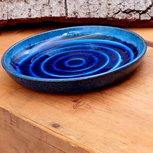 Könnte beinhalten: Eine blaue Keramikschale mit einem konzentrischen Kreisdesign. Die Schale ist glasiert und hat eine gesprenkelte Oberfläche.