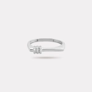 May include: A silver ring with a rectangular band and a horizontal bar design. Three small, round, clear stones are set in a vertical row on the bar. The ring has a minimalist and modern aesthetic.