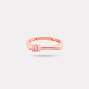 May include: Rose gold ring with a rectangular band and a cluster of three small, clear gemstones. The ring has a modern, minimalist design and is set against a plain white background.