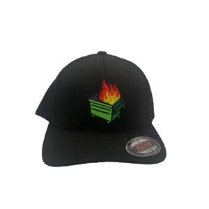 May include: Black baseball cap with an embroidered patch of a green dumpster on fire. The cap has a black Flexfit label on the back.