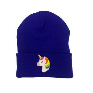 May include: A blue knitted beanie with a white unicorn with a rainbow mane and horn embroidered on the front.