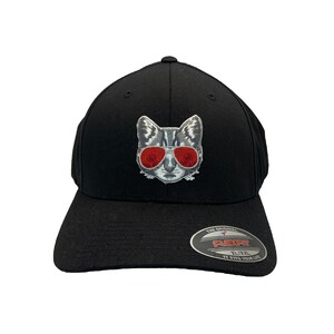 May include: Black baseball cap with a grey cat wearing red sunglasses embroidered on the front. The cap has a Flexfit label on the back with the text "The Original Flexfit XL/XXL It Fits Your Life."