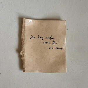 May include: A small, rectangular ceramic dish with a rough, textured edge. The dish is a speckled beige color and features handwritten black script that reads "No hay nadie como tu, mi amor."
