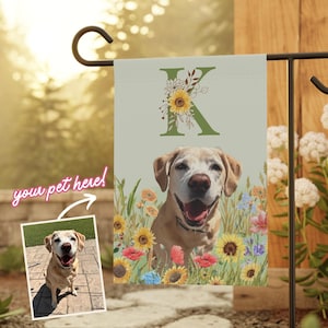 May include: A personalized garden flag with a green background and a large letter "K" decorated with sunflowers and other flowers. A yellow Labrador Retriever dog is pictured in the center of the flag. The text "you pet here!" is written in pink on the image.