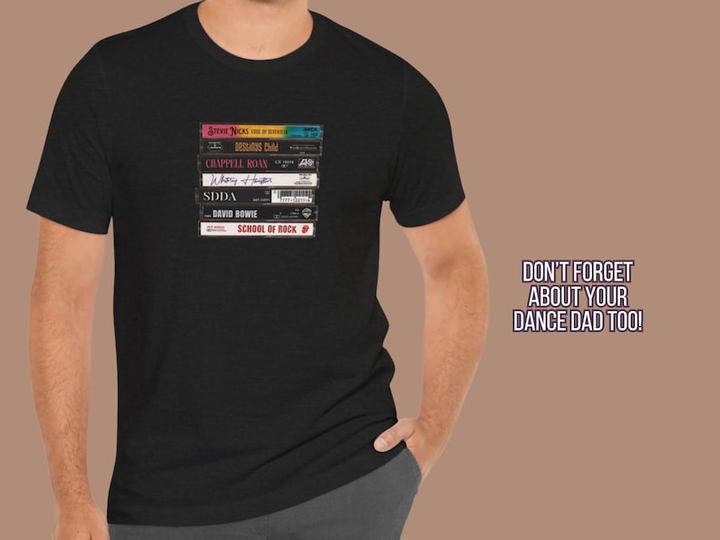 May include: A black t-shirt with a stack of cassette tapes featuring the band names "Journey", "Def Leppard", "Chappell Roan", "Whitney Houston", "SDDA", "David Bowie", and "School of Rock".