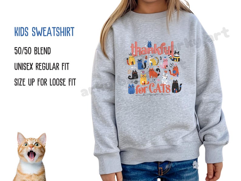 May include: A light gray kids' sweatshirt with the text "thankful for CATS" and various cartoon cat illustrations in multiple colors. The sweatshirt also has the text "KIDS SWEATSHIRT", "50/50 BLEND", "UNISEX REGULAR FIT", and "SIZE UP FOR LOOSE FIT".