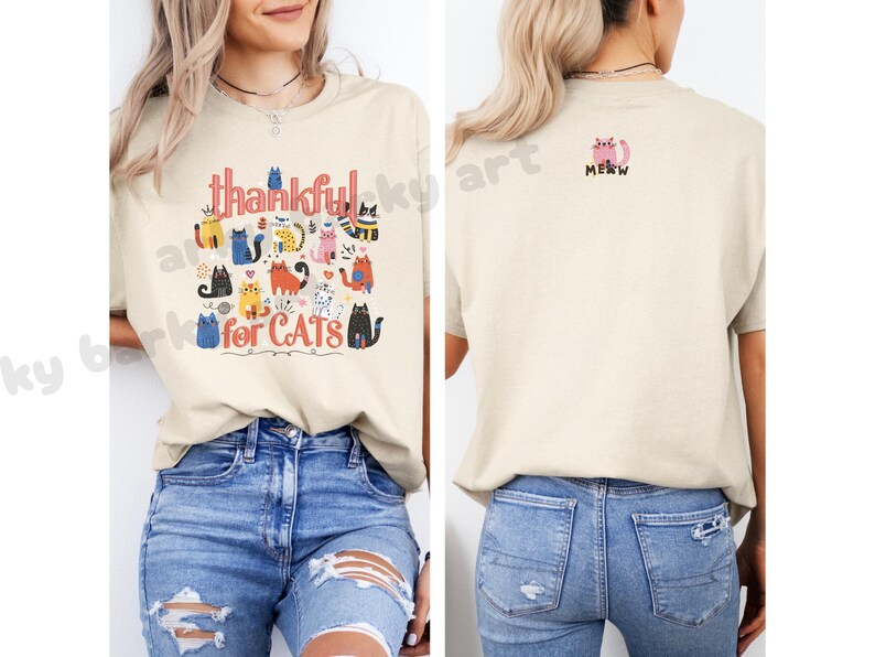 May include: Beige t-shirt with the words "thankful for CATS" and a colorful cat graphic. The back of the shirt has a pink cat graphic with the word "MEOW". The shirt is paired with blue jeans.