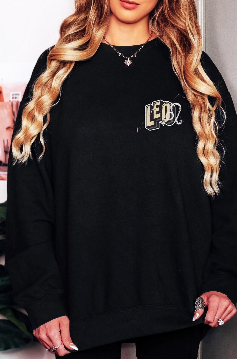 Puede incluir: Sudadera negra con un gr&aacute;fico dorado y negro del signo zodiacal Leo.