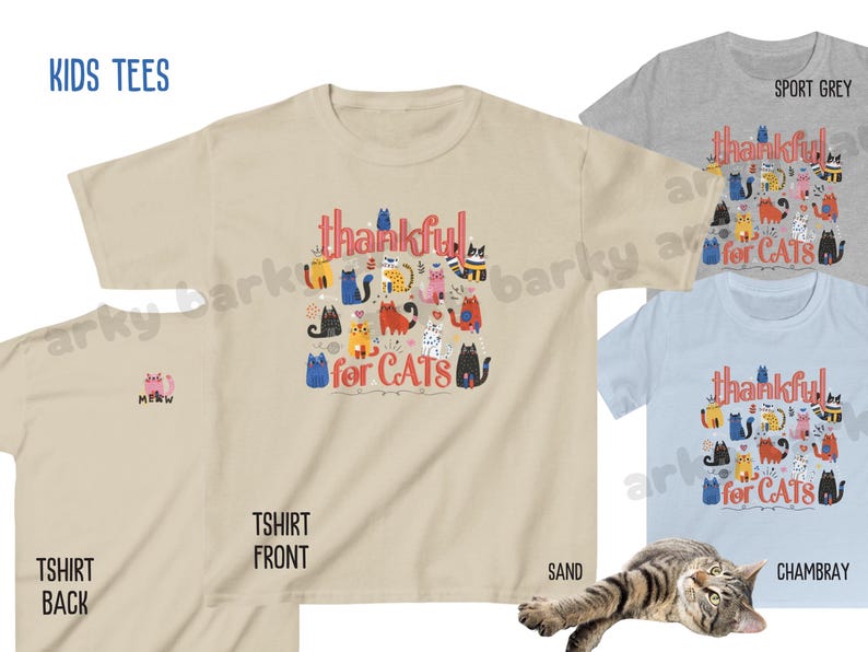 May include: A collection of kids' t-shirts in various colors, including sand, sport grey, and chambray. The front of the sand-colored shirt features the text "thankful for CATS" with colorful cat illustrations. The back of the sand shirt has a small "MEOW" graphic.
