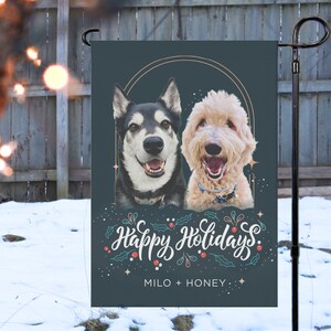 May include: A decorative garden flag featuring two dogs, a Husky and a Goldendoodle, with the words "Happy Holidays" in white script. The flag is dark teal with a gold circular design and the names "Milo + Honey" at the bottom.