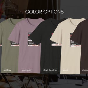 May include: A selection of t-shirts in various colors, each featuring a graphic of a stack of cassette tapes with the text "The Rolling Stones" and "School of Rock". The colors include charcoal, military, paragon, black heather, sand, and chocolate.