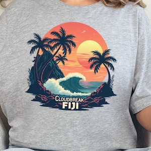 May include: A grey t-shirt featuring a graphic of a sunset over a beach with palm trees and the text "Cloudbreak FIJI".