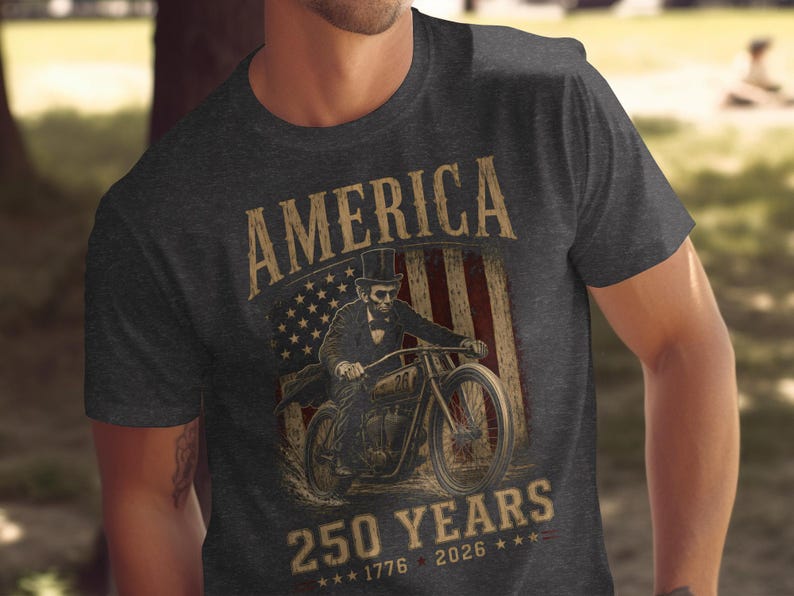 Man in patriotic t-shirt featuring Abraham Lincoln on a motorcycle, American flag, and text.