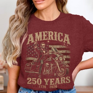 Maroon t-shirt with graphic of man on motorcycle, American flag, and "America 250 Years" text.