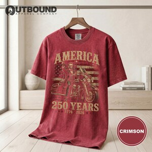 Red t-shirt with "America 250 Years 1776-2026" graphic and motorcycle rider.