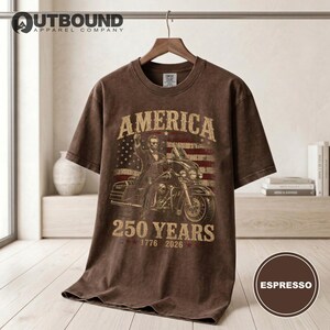 Brown t-shirt with Abraham Lincoln riding a motorcycle and American flag, "America 250 Years 1776-2026".