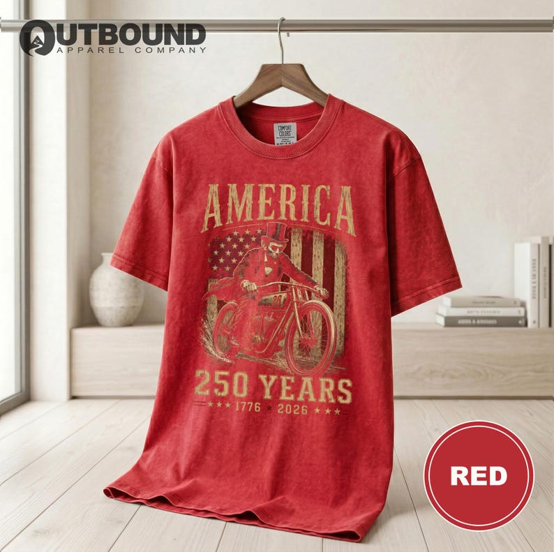 Red t-shirt with "America 1776-2026" and motorcyclist graphic.