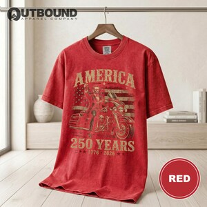 Red t-shirt with "America 250 Years 1776-2026" text and motorcycle graphic.