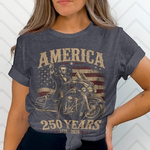 Abraham Lincoln riding a motorcycle with "America 250 Years 1776-2026" text.