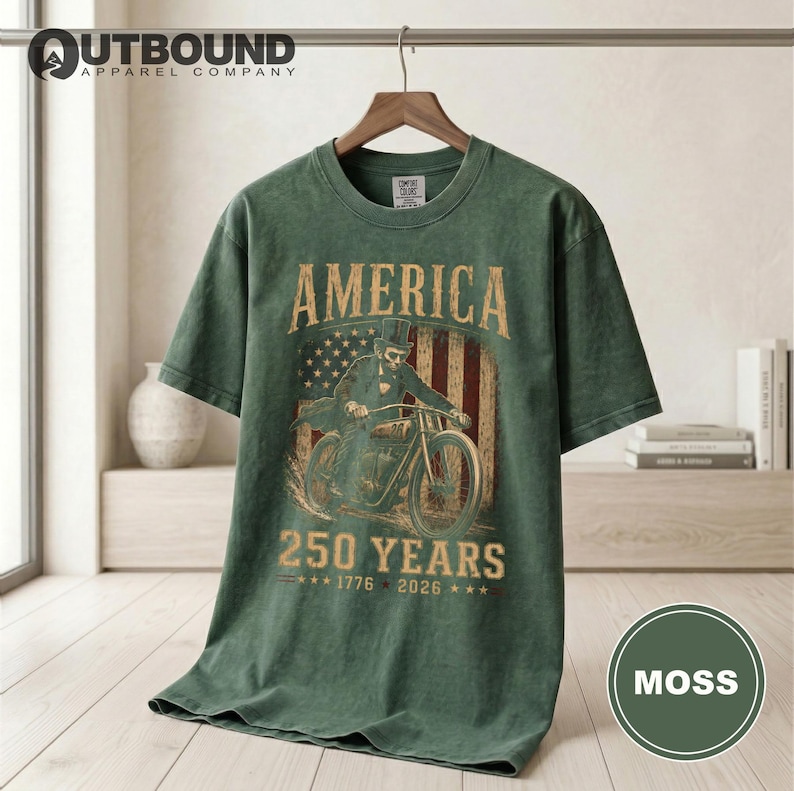 Green t-shirt with "America 250 Years 1776 2026" graphic.
