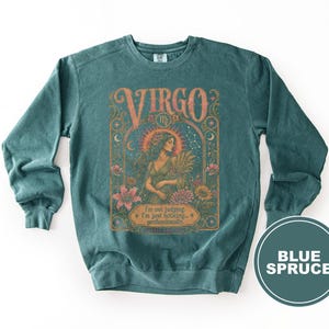 Teal sweatshirt with "Virgo" design, a woman holding wheat, and text.